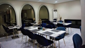 A dining area with tables and chairs, large arched windows, and a modern interior design. - Crevice Hotel (Davao)