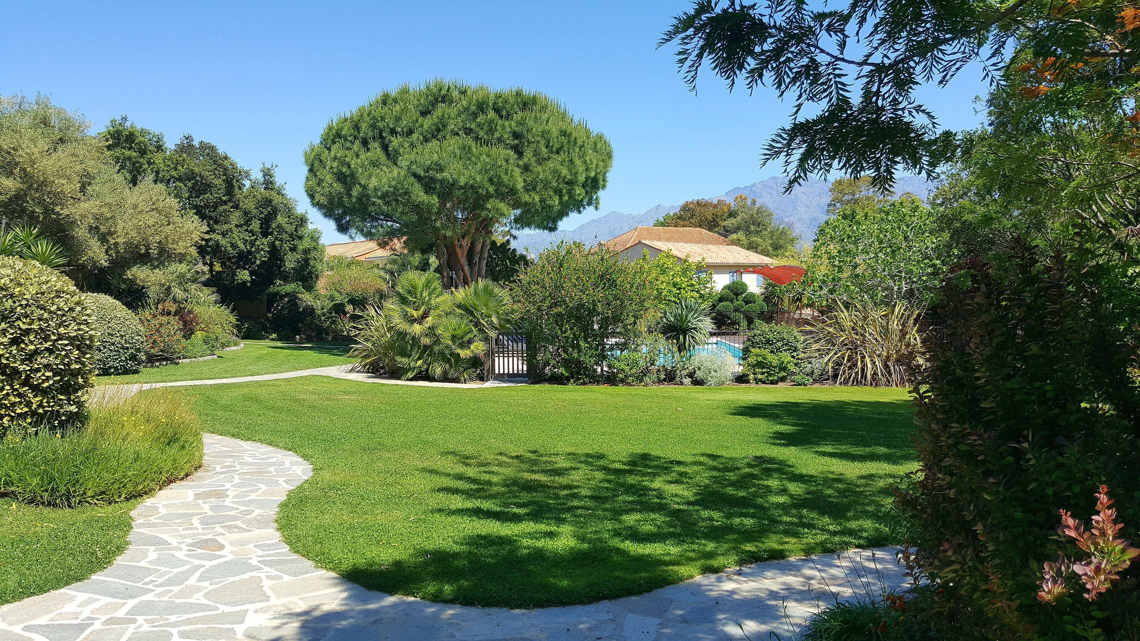 Un jardin aménagé avec un sentier en pierre menant à une maison au toit rouge.
