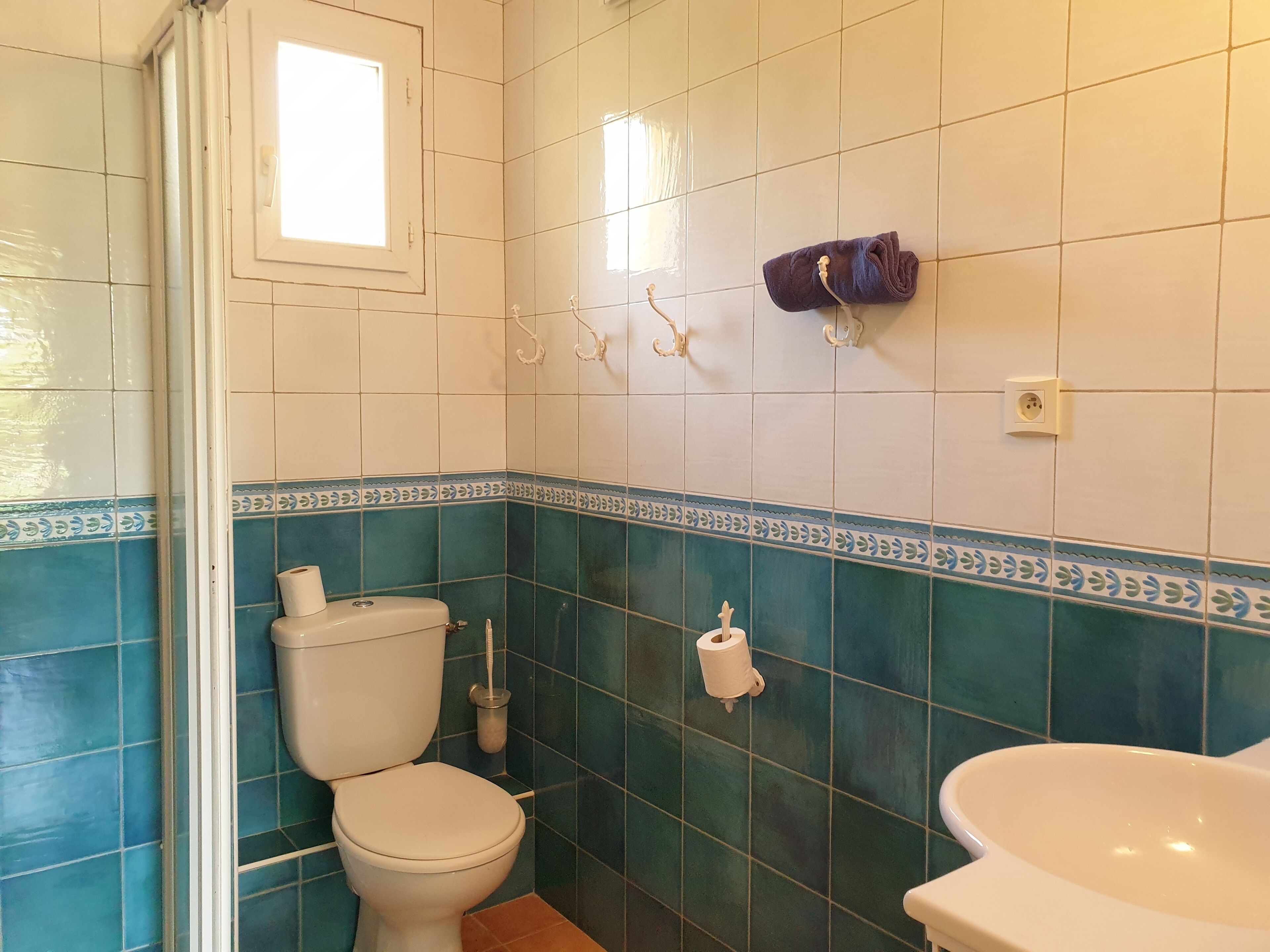Un baño con inodoro, lavamanos y toallero.