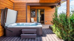 A wooden deck with a hot tub, steps, and a door leading to an interior room. - Yellowstone Trail - Great Home Overlooking the Yellowstone River (Pray)