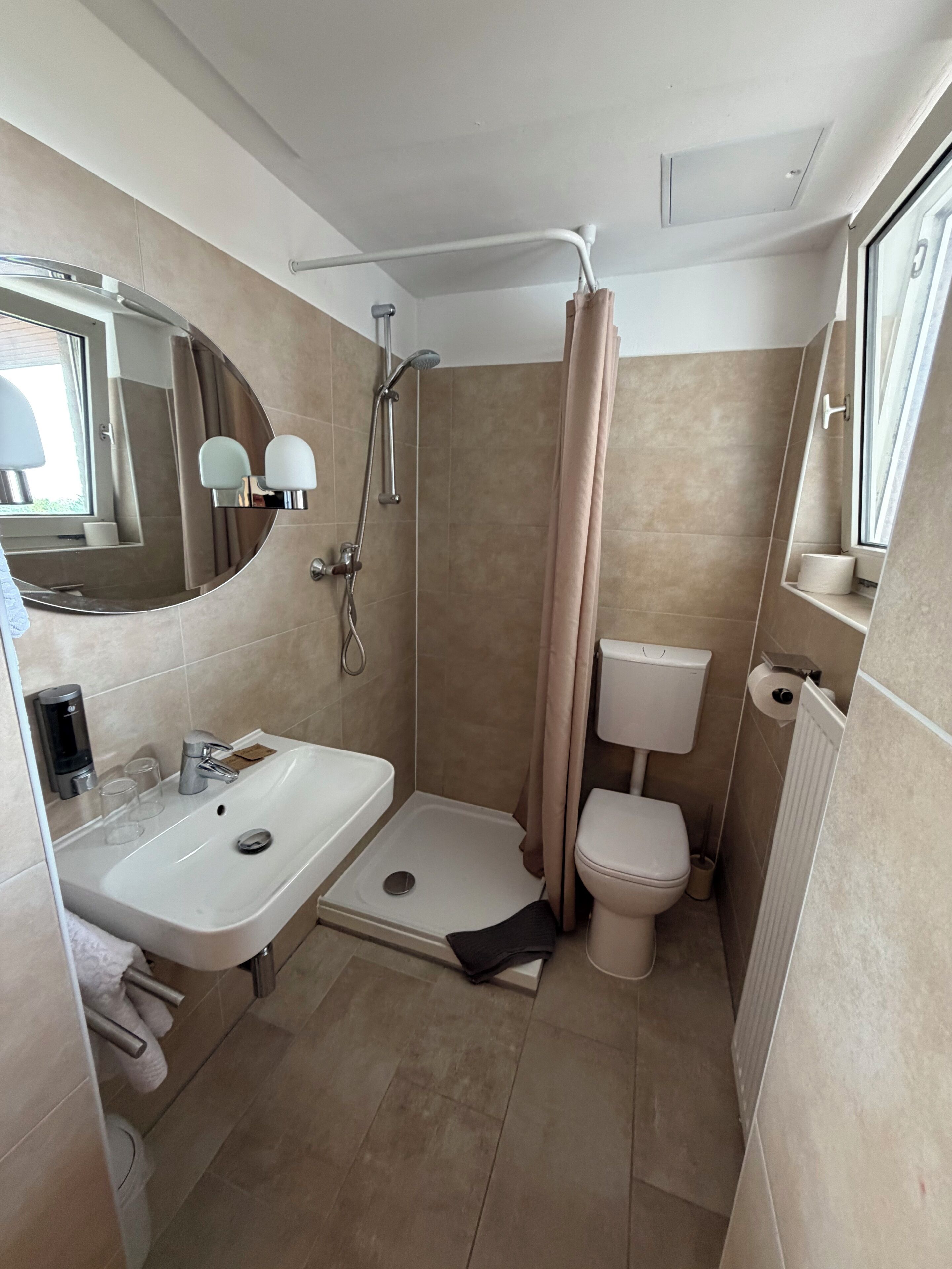 Ein Badezimmer mit Dusche, Toilette, Waschbecken und Spiegel.