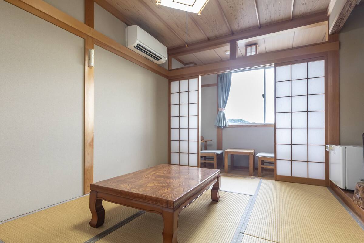 Una habitación tradicional japonesa con suelo de tatami, una mesa de madera y puertas correderas.
