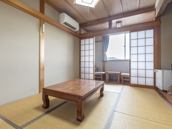 A traditional Japanese room with tatami flooring, a wooden table, and sliding doors.