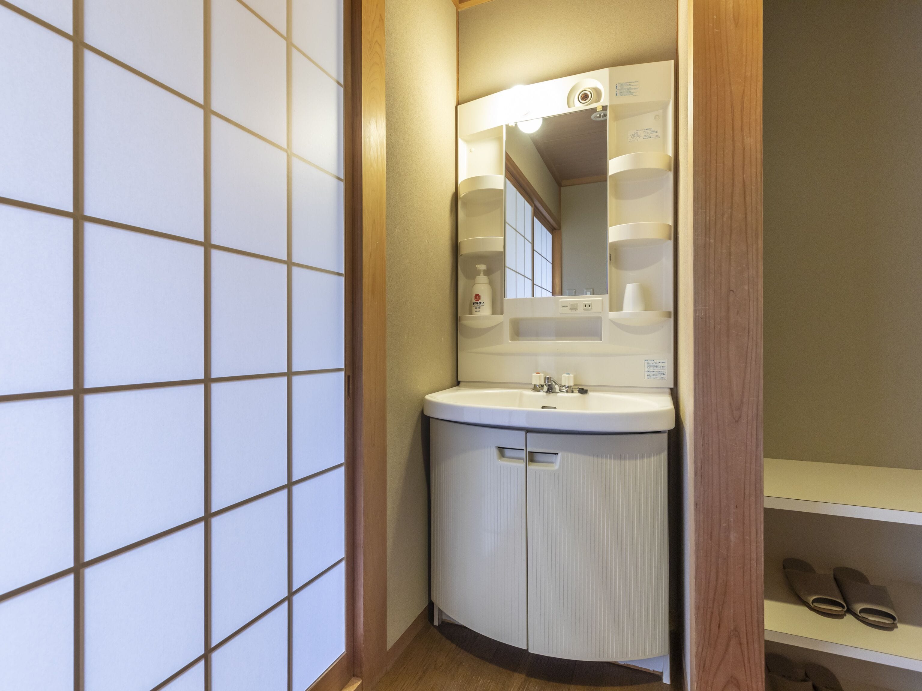 Un baño pequeño con lavamanos, espejo y repisas.