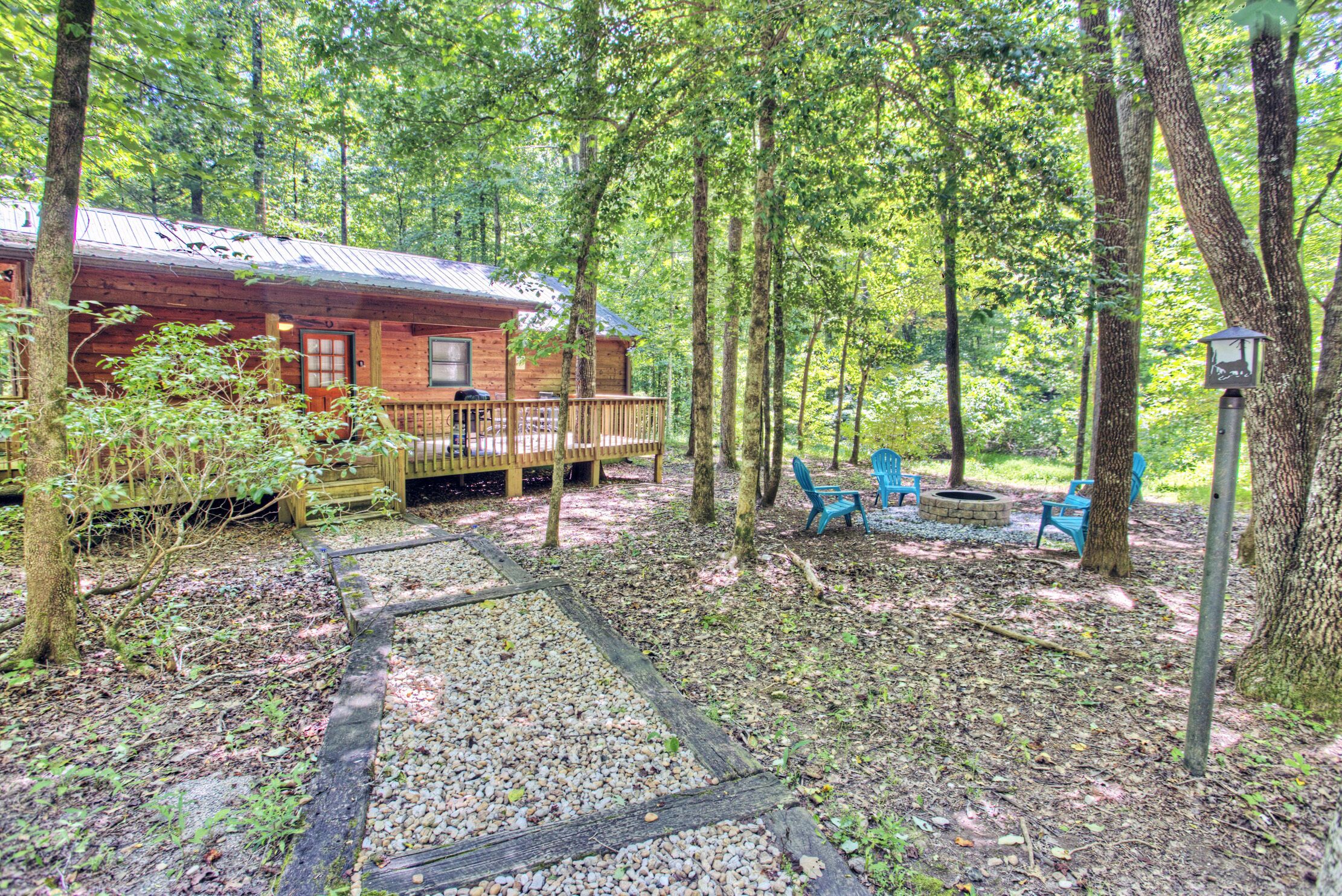 Eine Hütte mit Terrasse, umgeben von Bäumen und Sitzgelegenheiten im Freien.