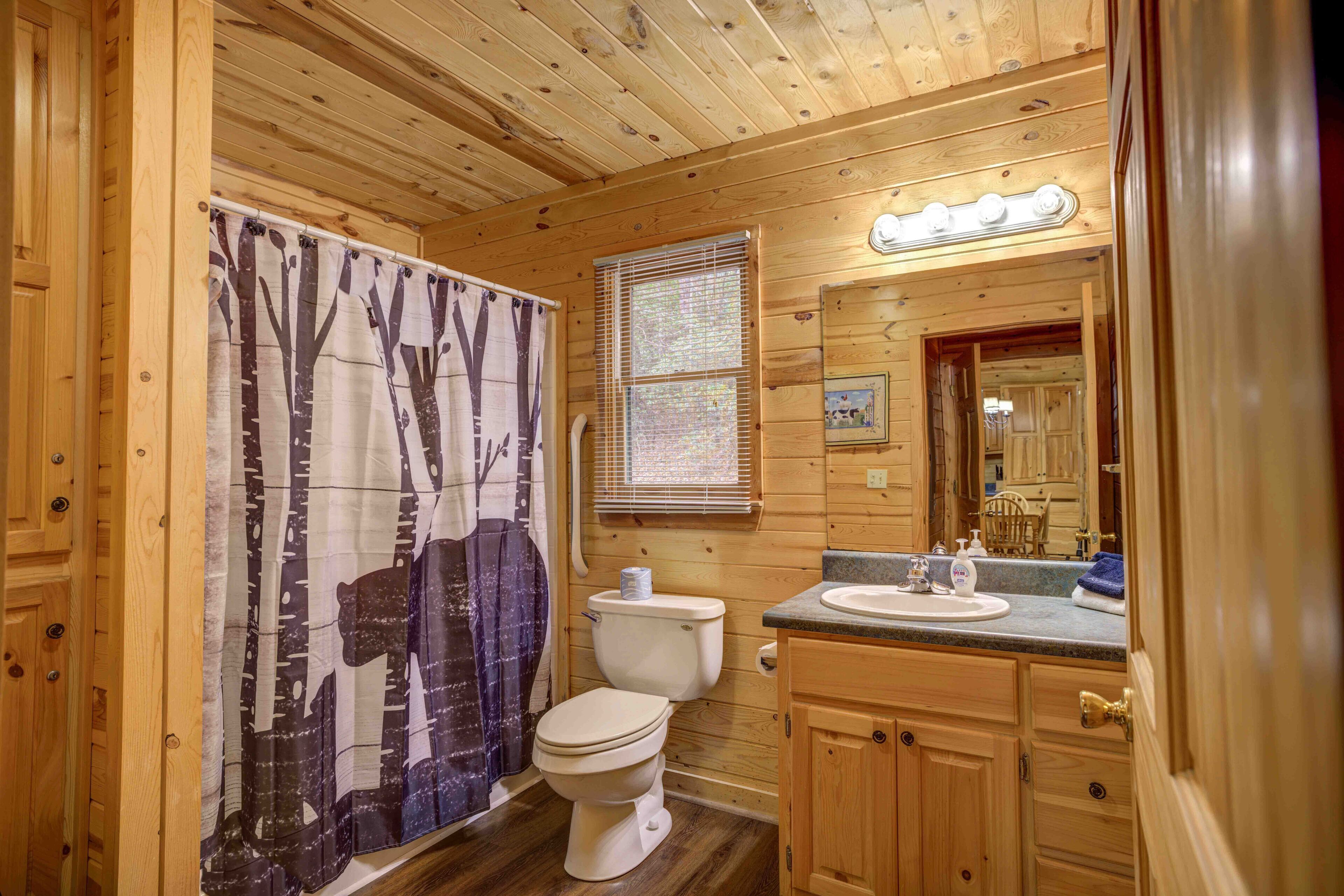 Ein Badezimmer einer Holzhütte mit Toilette, Waschbecken und Duschvorhang.