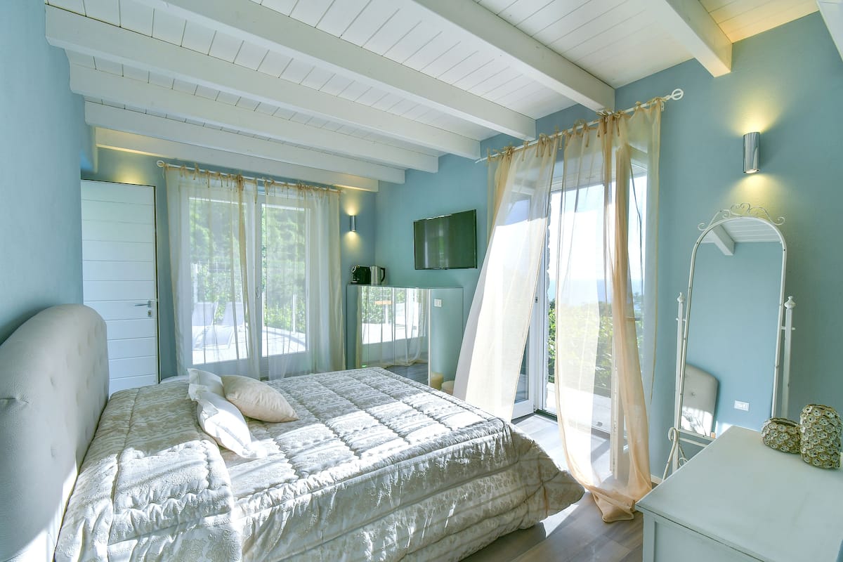 A bedroom with a bed, a dresser, a mirror, and a television on the wall.