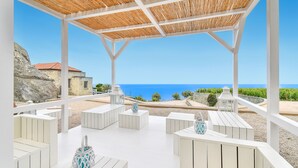 A covered outdoor seating area with white furniture and a view of the sea. - Tenuta C'est la Vie (Forio)