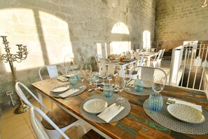 A dining area with a rustic wooden table set for a meal, surrounded by white chairs. - Tenuta C'est la Vie (Forio)
