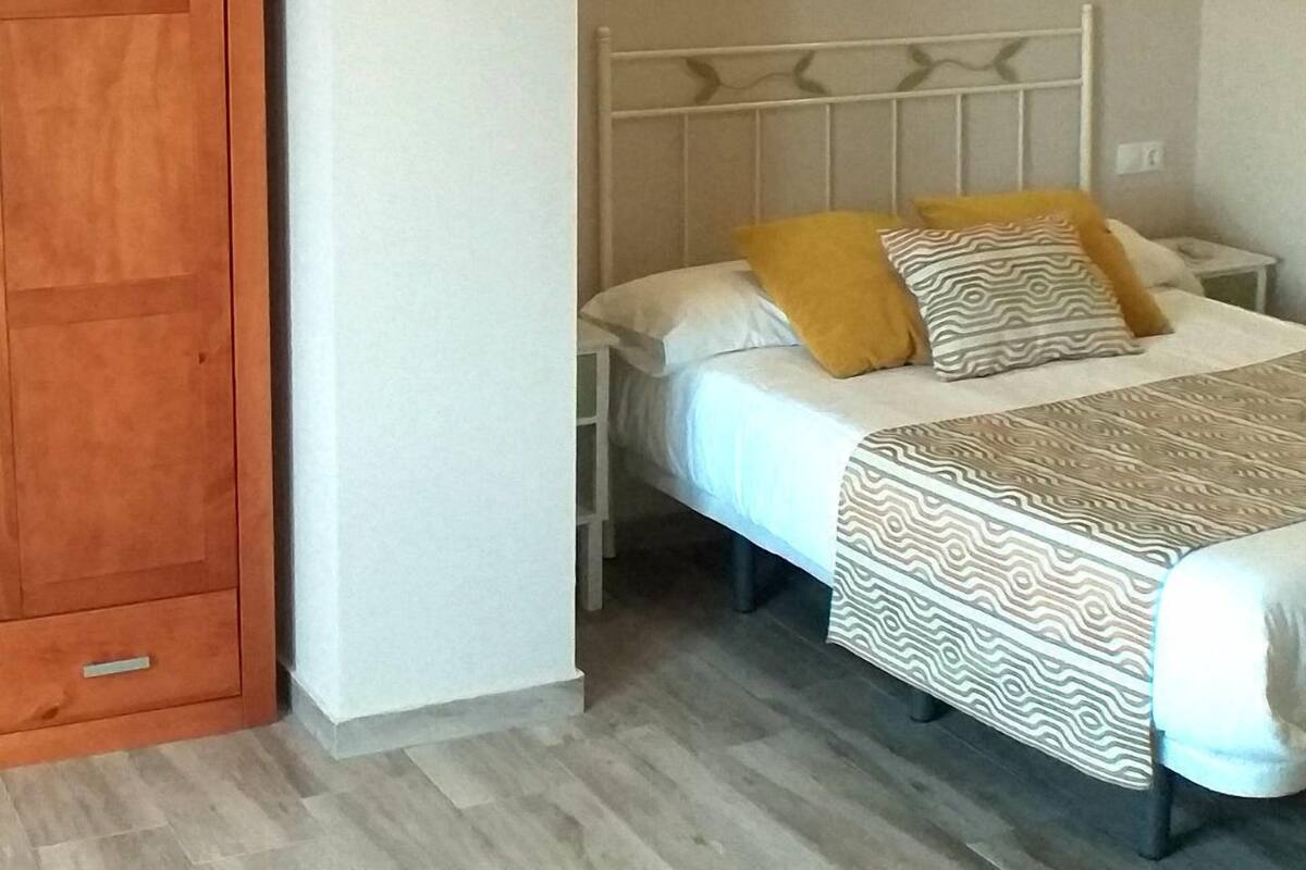 A bedroom with a bed, wooden wardrobe, and decorative wall sconces.