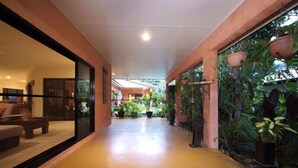 Un couloir avec une paroi en verre d’un côté et un mur décoré de jardinières suspendues.