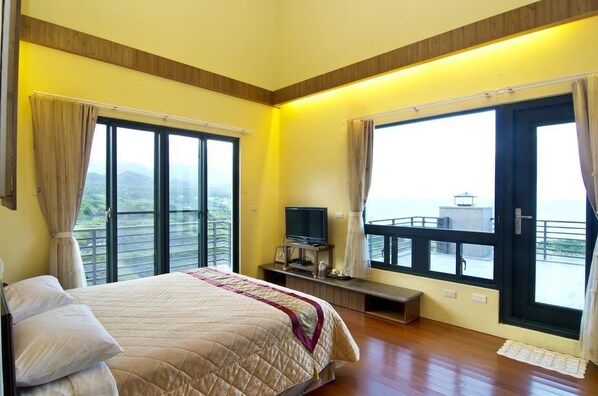 A bedroom with a bed, a television on a stand, and large windows with curtains. - Flrice Villa (Changbin)