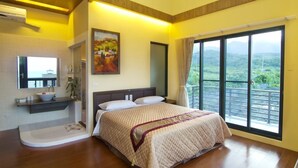 Une chambre avec un grand lit, une salle de bain avec un lavabo et un miroir, et un balcon avec vue.