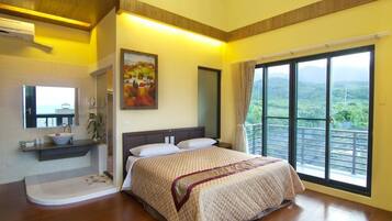 A bedroom with a large bed, a bathroom with a sink and mirror, and a balcony with a view.