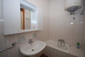 A bathroom with a sink, mirror, and bathtub. - Villa Ralph (Lignano Sabbiadoro)