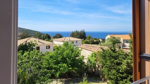 A view from a balcony overlooking a coastal town with terracotta-roofed buildings and lush greenery. - Villa Primavera (Galeria)