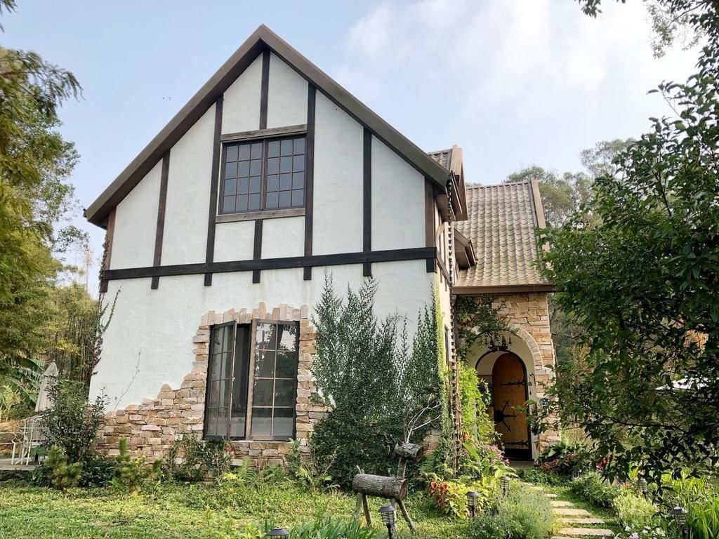A traditional half-timbered house with a stone archway and a well-maintained garden.