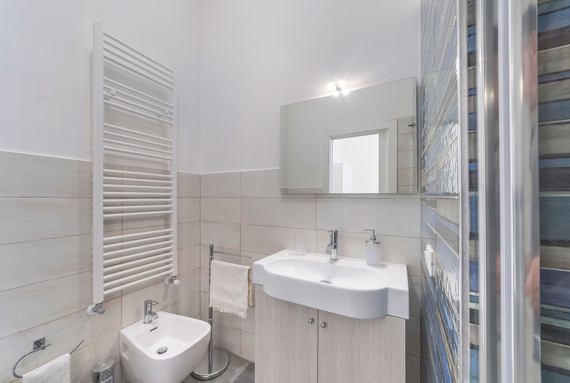 Een moderne badkamer met een wit wastafelmeubel, een toiletbril en een douchecabine met glazen wanden.