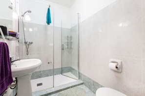 A modern bathroom with a glass-enclosed shower, a white sink, and a toilet. - D View 4 You (Mellieha)