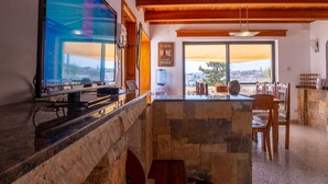 A modern kitchen with a stone island, wooden ceiling, and a large window offering a city view. - D View 4 You (Mellieha)