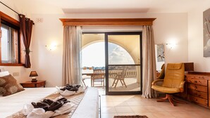 A hotel room with a bed, a chair, a dresser, and a balcony with a view. - D View 4 You (Mellieha)