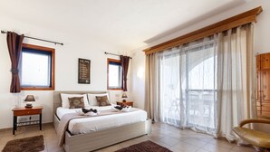 A bedroom with a bed, nightstands, a chair, and a large window with curtains. - D View 4 You (Mellieha)