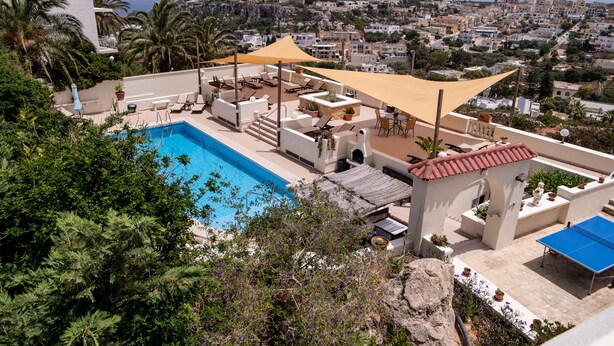 A rooftop pool area with lounge chairs and a view of the city. - D View 4 You (Mellieha)