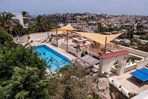 A rooftop pool area with lounge chairs and a view of the city. - D View 4 You (Mellieha)