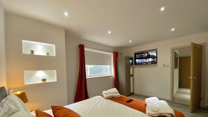 Ein Hotelzimmer mit einem Bett, zwei Nachttischen, einem Fernseher und einem Kleiderschrank.