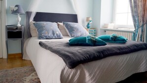 A bedroom with a bed, a nightstand, a lamp, and a window with curtains. - Maison du Carrec (Paimpol)