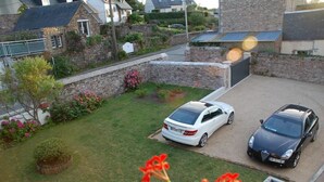 A residential driveway with two cars parked, surrounded by a well-maintained lawn and stone walls. - Maison du Carrec (Paimpol)