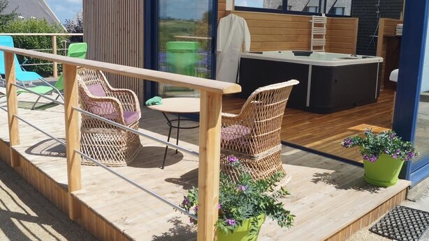 A deck with wicker chairs, a small table, and potted plants. - Maison du Carrec (Paimpol)