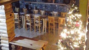L’intérieur d’un chalet rustique, avec un mur en pierre, des bancs en bois et un sapin de Noël décoré.