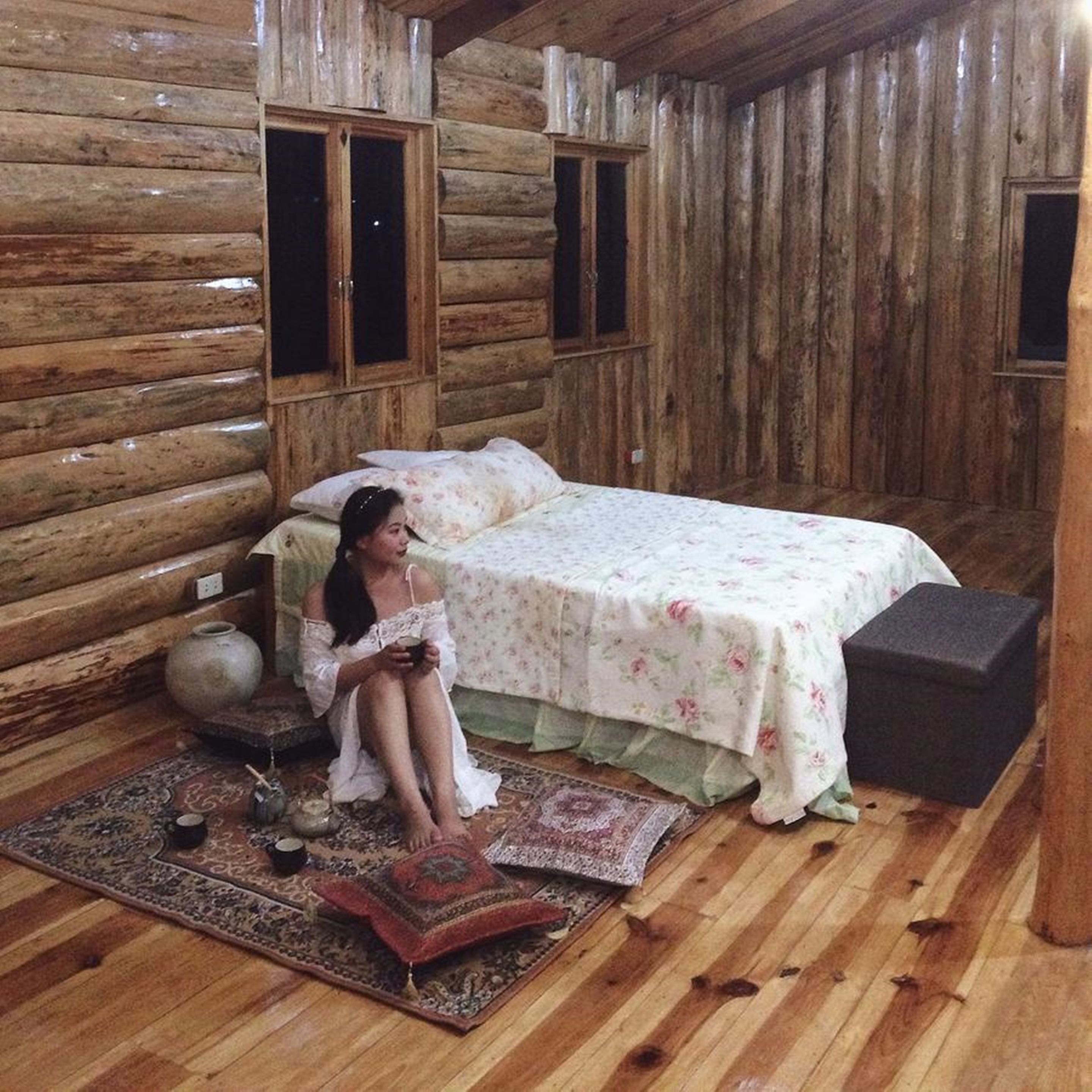 Una habitación tipo cabaña de madera con una cama, un rincón de descanso y una alfombra.
