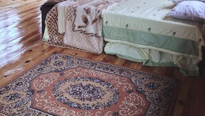 Une cabane rustique en bois, avec deux lits, une grande moquette et un plafond en bois agrémenté de luminaires suspendus.