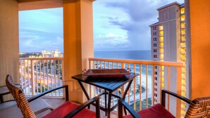 A balcony with a table and chairs, overlooking a cityscape and the ocean. - Clam Shell at Grand Panama - Intimate and Serene Perfect spot for relaxing (Panama City Beach)