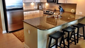 A modern kitchen with a central island, stainless steel appliances, and bar stools. - Clam Shell at Grand Panama - Intimate and Serene Perfect spot for relaxing (Panama City Beach)