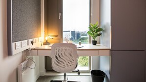 A modern office space with a desk, chair, and a potted plant by a window. - Axo Paradise village (Coventry)