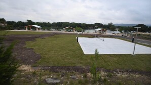 A park with a paved area, benches, and a lake in the background. - Cabin 4 of 7 With Private River Access to the Nueces River (Uvalde)