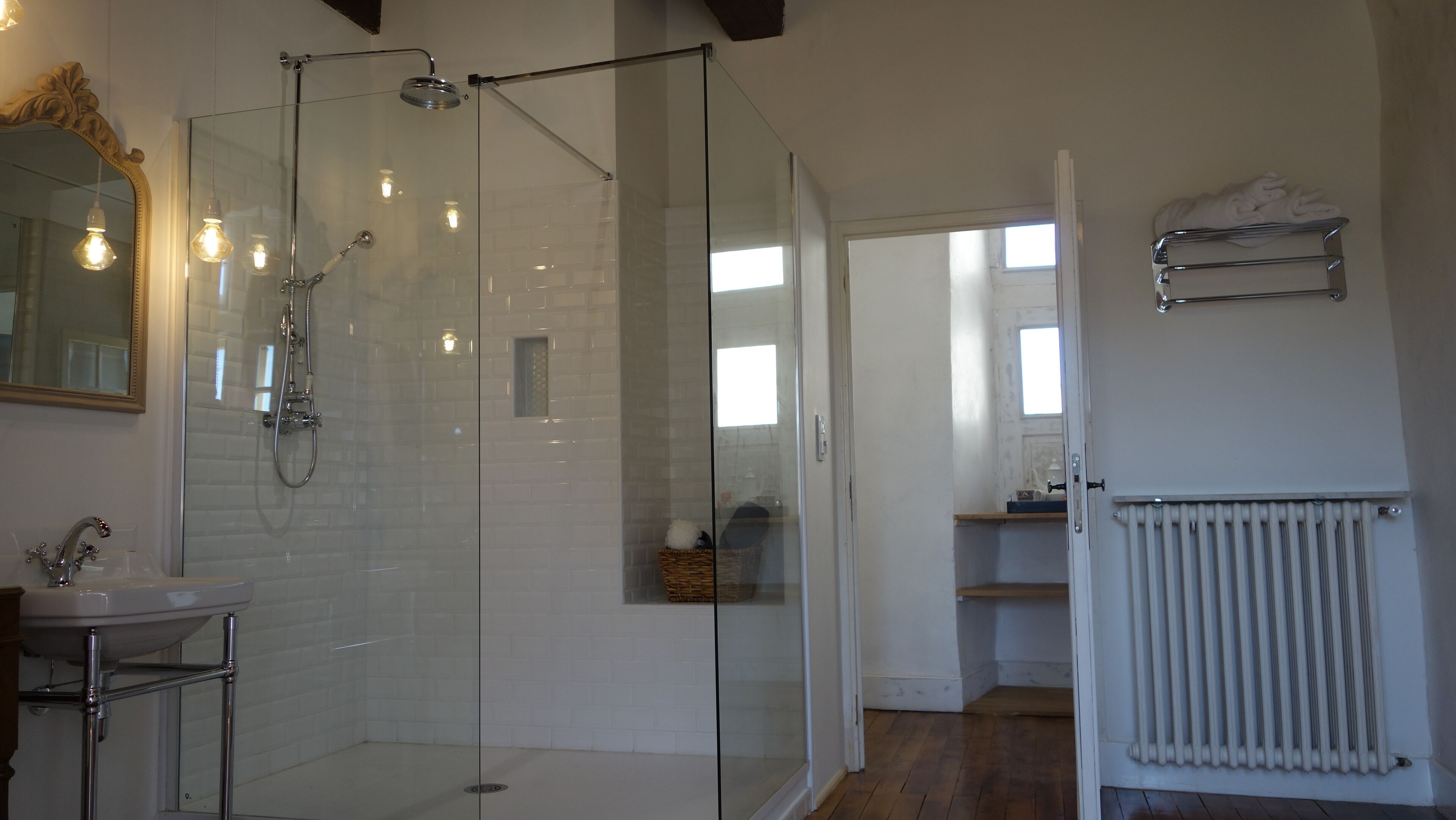 A modern bathroom with a glass-enclosed shower, a white sink, and a mirror with an ornate frame.