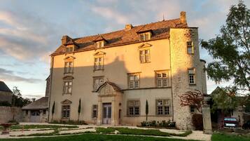 Stately building with a central entrance and evenly spaced windows, set amidst a serene lawn and mature trees.