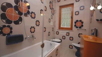 A bathroom with a bathtub, toilet, and sink, decorated with floral patterns on the walls and floor.