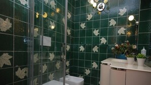 Ein Badezimmer mit grünen Fliesen, einer Toilette, einem Bidet und einem Waschbecken mit Spiegel.