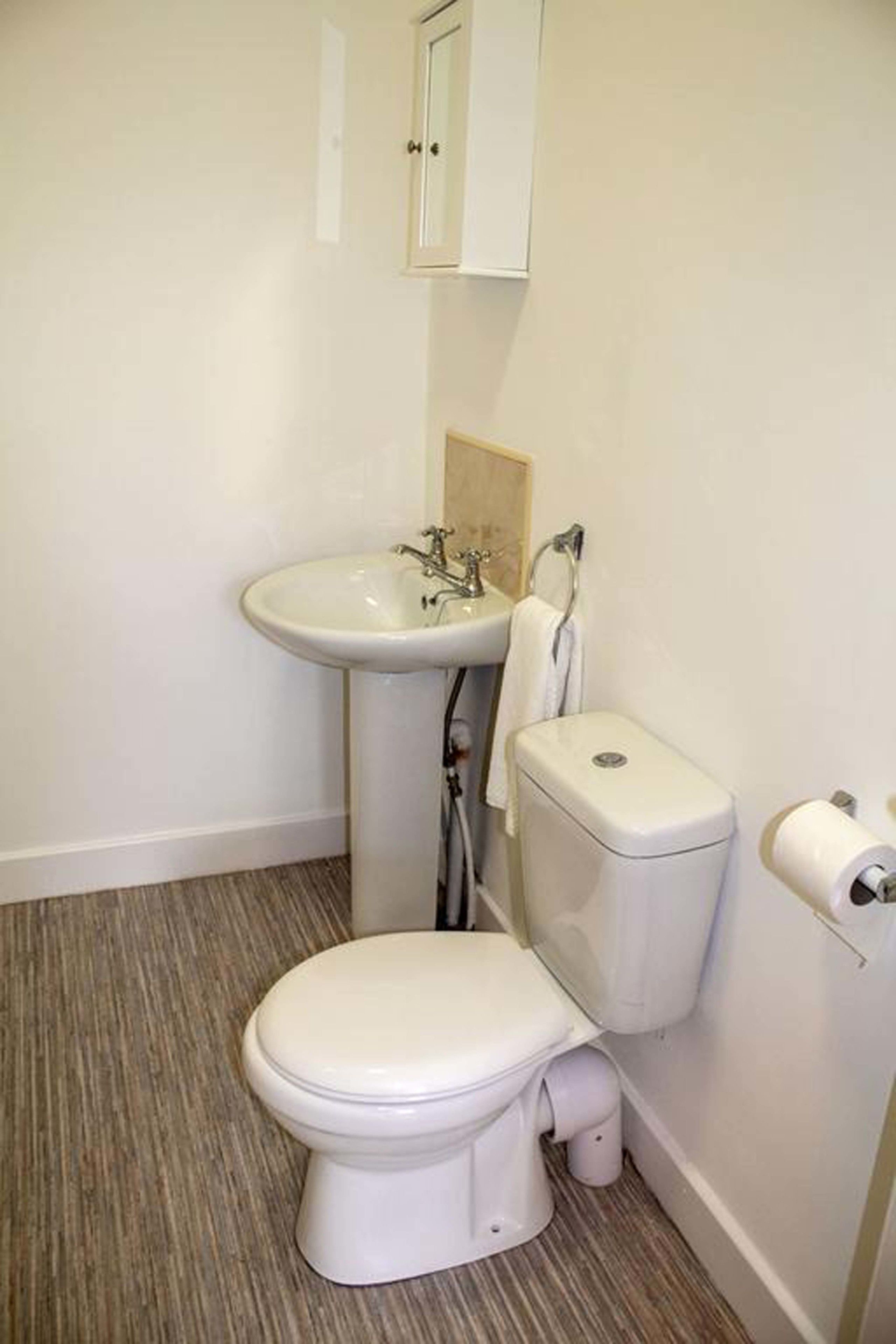 Un baño pequeño y limpio con inodoro, lavabo y armario.