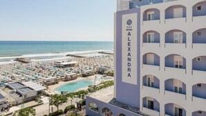 Ein Hotel namens 'HOTEL ALEXANDRA' mit Pool, Meerblick und mehreren Balkonen.