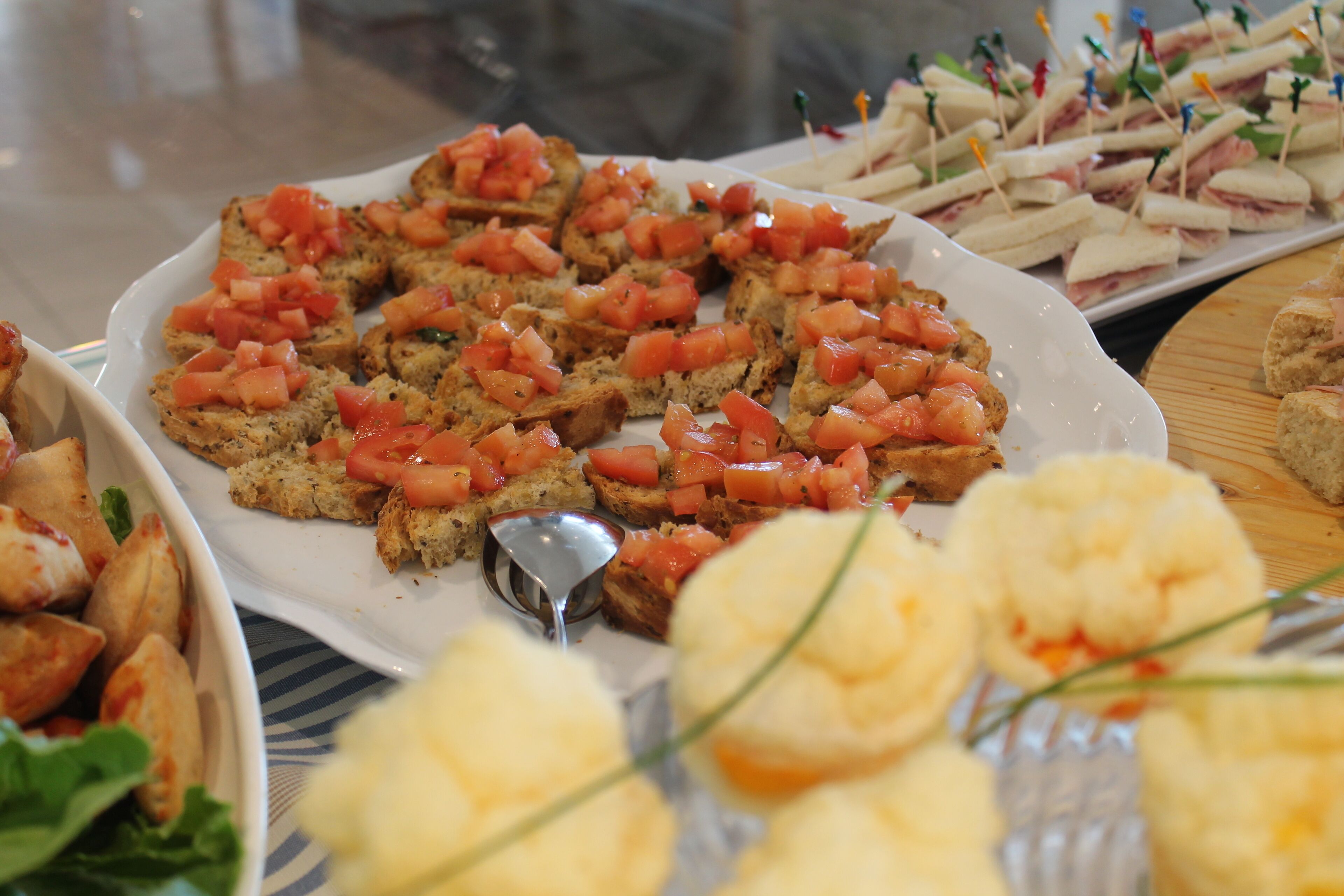 A variety of food items on a table, including bread with tomato and cheese, sandwiches, and other snacks.