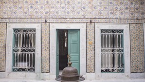 Une façade d’immeuble avec trois portes, chacune dotée d’une grille métallique et d’une porte verte.