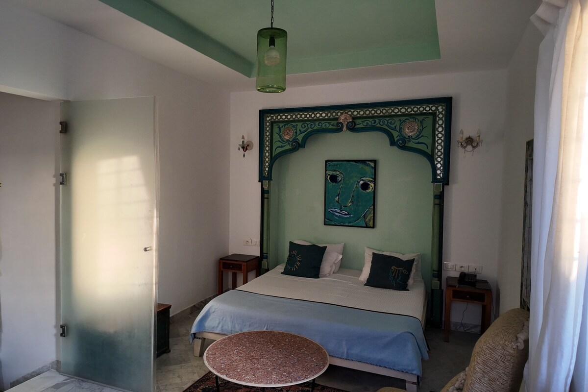 A bedroom with a bed, a round table, and a wardrobe.