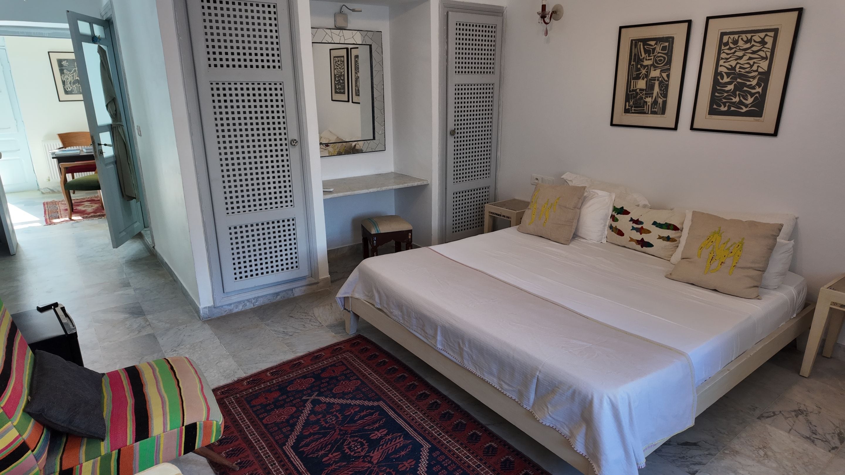 A bedroom with a bed, pillows, a rug, and artwork on the wall.