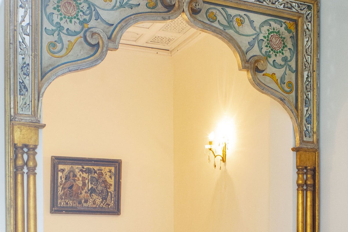 A room with a bed, a wall-mounted light, and a framed picture.